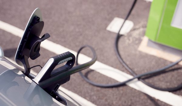 Close Up Of Power Cable Charging Electric Car Outdoors In Supermarket Car Park